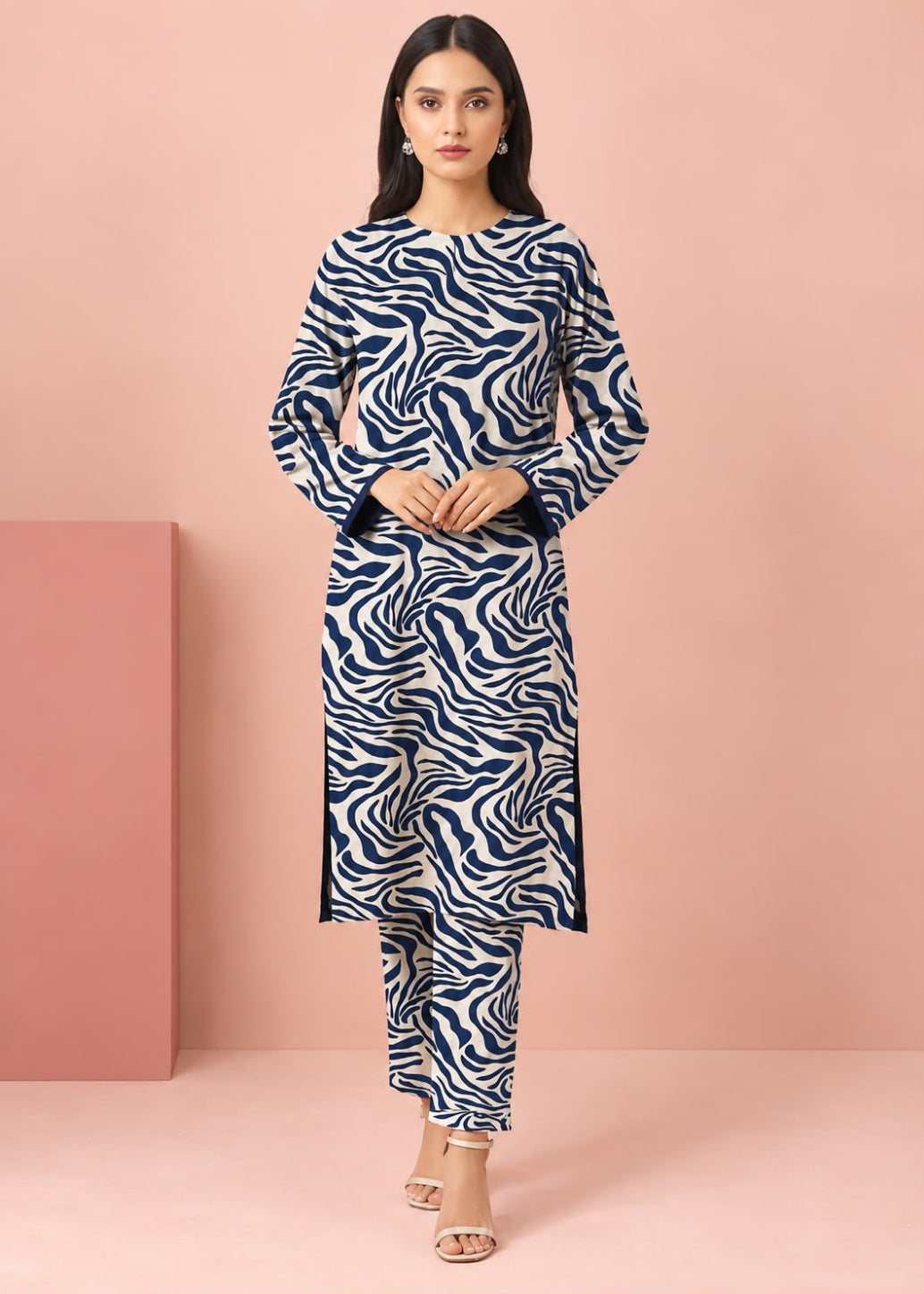 A woman modeling a navy blue and white zebra-print kurta set with matching pants, standing against a solid pink studio backdrop.