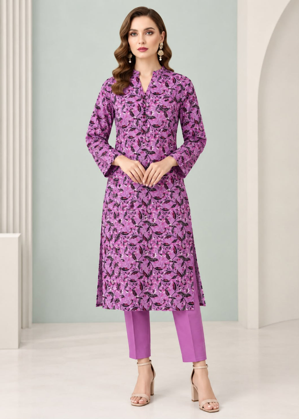 A woman modeling a purple and black floral print kurta with matching purple pants, standing in a clean, modern studio setting with light gray walls and white columns.