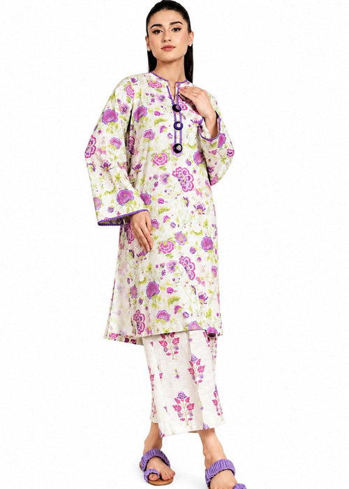 A woman modeling a traditional Indian outfit consisting of a cream-colored kurta and pant set with a vibrant pink, purple, and green floral print. The kurta features a mandarin collar and a decorative black and purple embroidered placket.