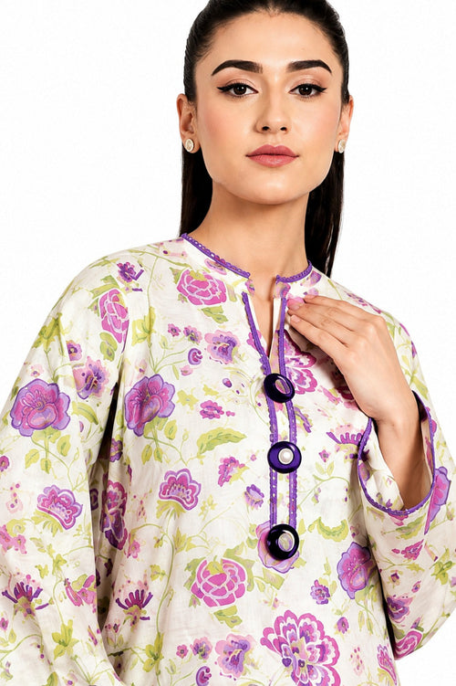 A woman wearing a cream-colored tunic top with a purple and green floral print, featuring a purple mandarin collar and three large purple buttons on the front.