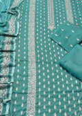 A teal green salwar suit fabric set laid flat, featuring a printed body fabric with vertical white and silver paisley borders and small motifs, matching folded fabric pieces, and a draped dupatta with ornate border patterns.