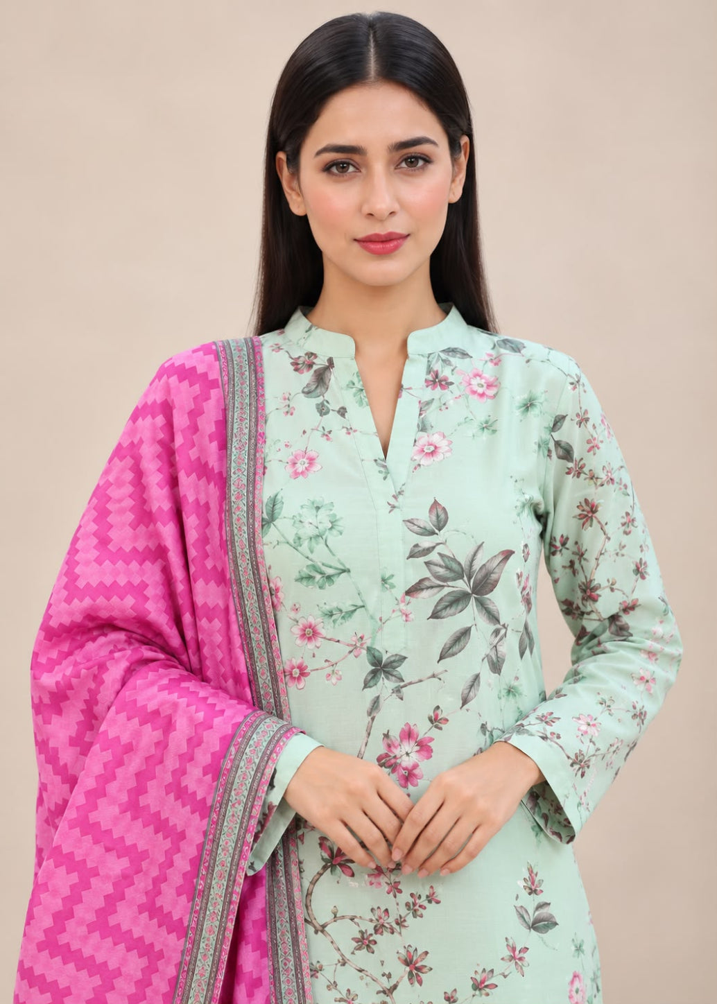 A woman modeling a mint green floral printed kurta with a bright pink patterned dupatta, set against a solid beige background.