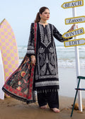 A woman stands on a sandy beach wearing a black and white embroidered traditional outfit with a red patterned dupatta. A large white directional signpost with words including SPA, BEACH, Zareen, WINTER, and EDIT is beside her, with surfboards and the ocean in the background.