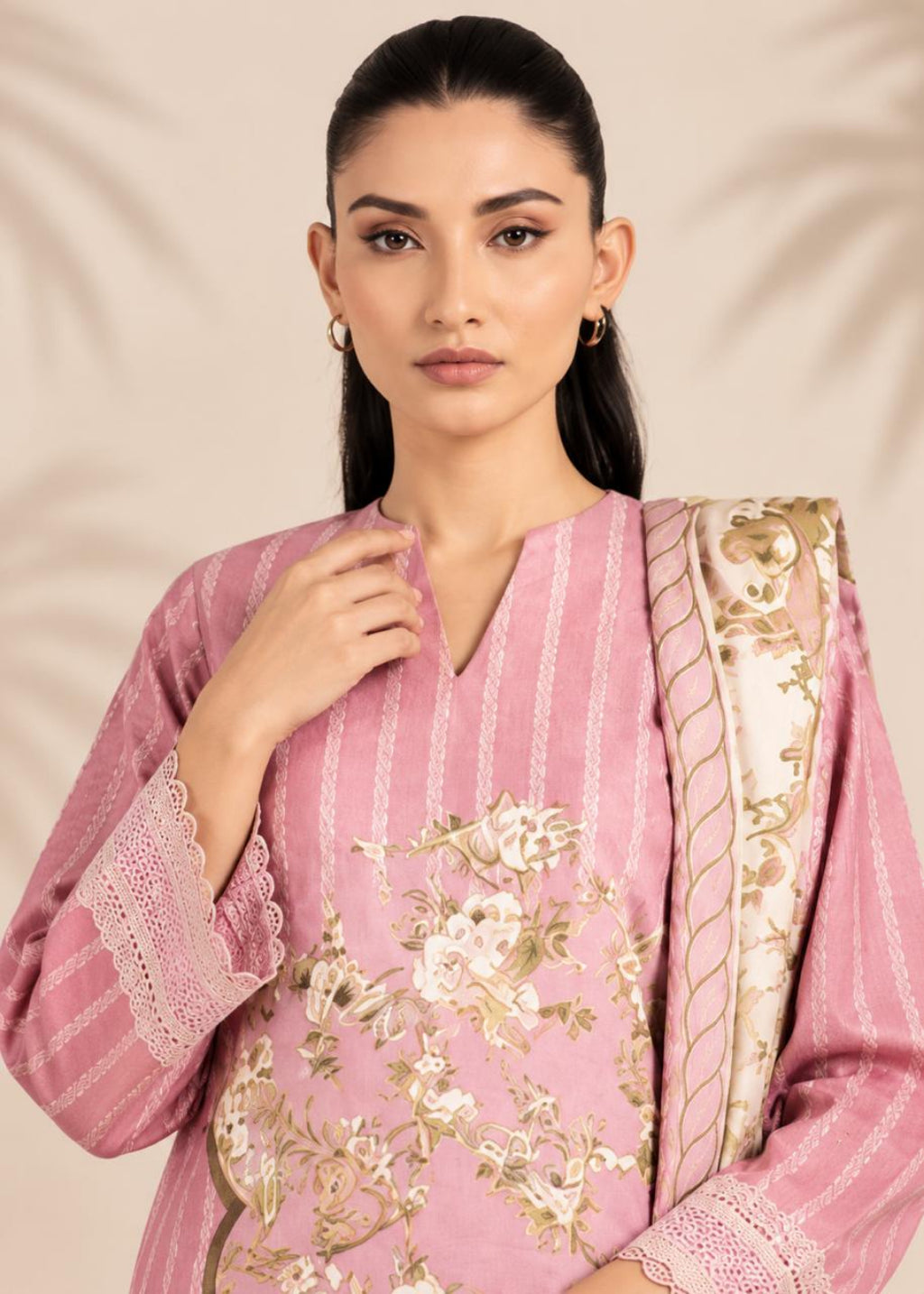 A woman modeling a pink embroidered kurta with vertical stripes and floral detailing, paired with a beige and gold patterned dupatta, against a soft beige background.