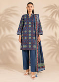 A woman modeling a three-piece traditional outfit consisting of a blue patterned kurta, matching blue trousers, and a coordinating dupatta, set against a beige background with palm leaf shadows.