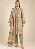 A woman modeling a traditional three-piece outfit featuring a long-sleeved printed tunic in sage green with pink and beige floral motifs, paired with matching sage green trousers and a coordinating dupatta with tassels, set against a solid beige studio background.