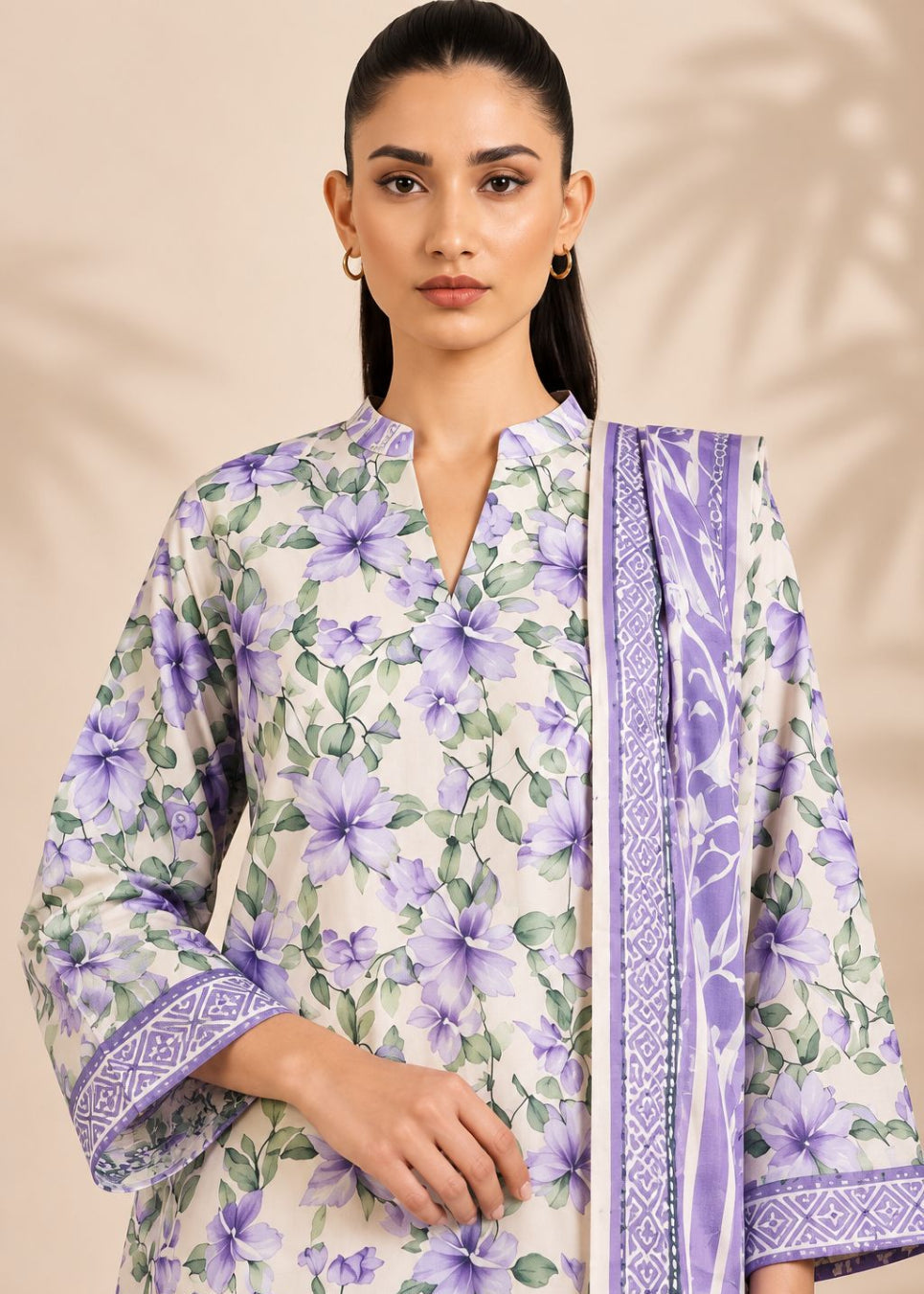 A woman modeling a traditional three-piece salwar kameez suit in lavender and white. The kurta features a purple floral print on a white base, with matching patterned borders on the sleeves and collar, paired with a coordinating dupatta.