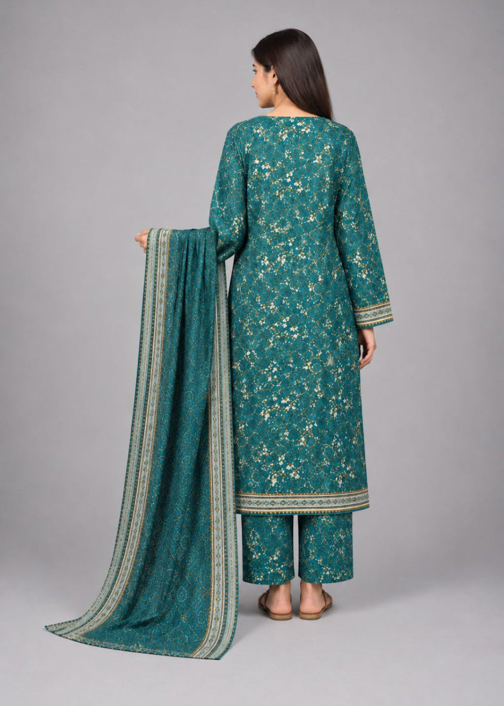 A woman shown from the back wearing a teal green ethnic three-piece suit with beige floral embroidery and a matching dupatta, set against a solid gray studio background.