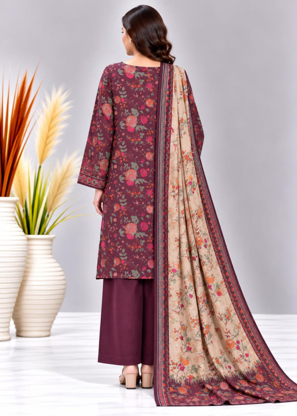 A woman shown from the back wearing a floral printed salwar kameez suit with a matching dupatta. The kurta and trousers are deep maroon, while the dupatta is beige with a floral print and a maroon border.