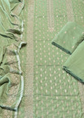 A sage green salwar suit set laid out flat, featuring a printed fabric body, matching pleated dupatta, and two folded fabric pieces with embroidered borders.