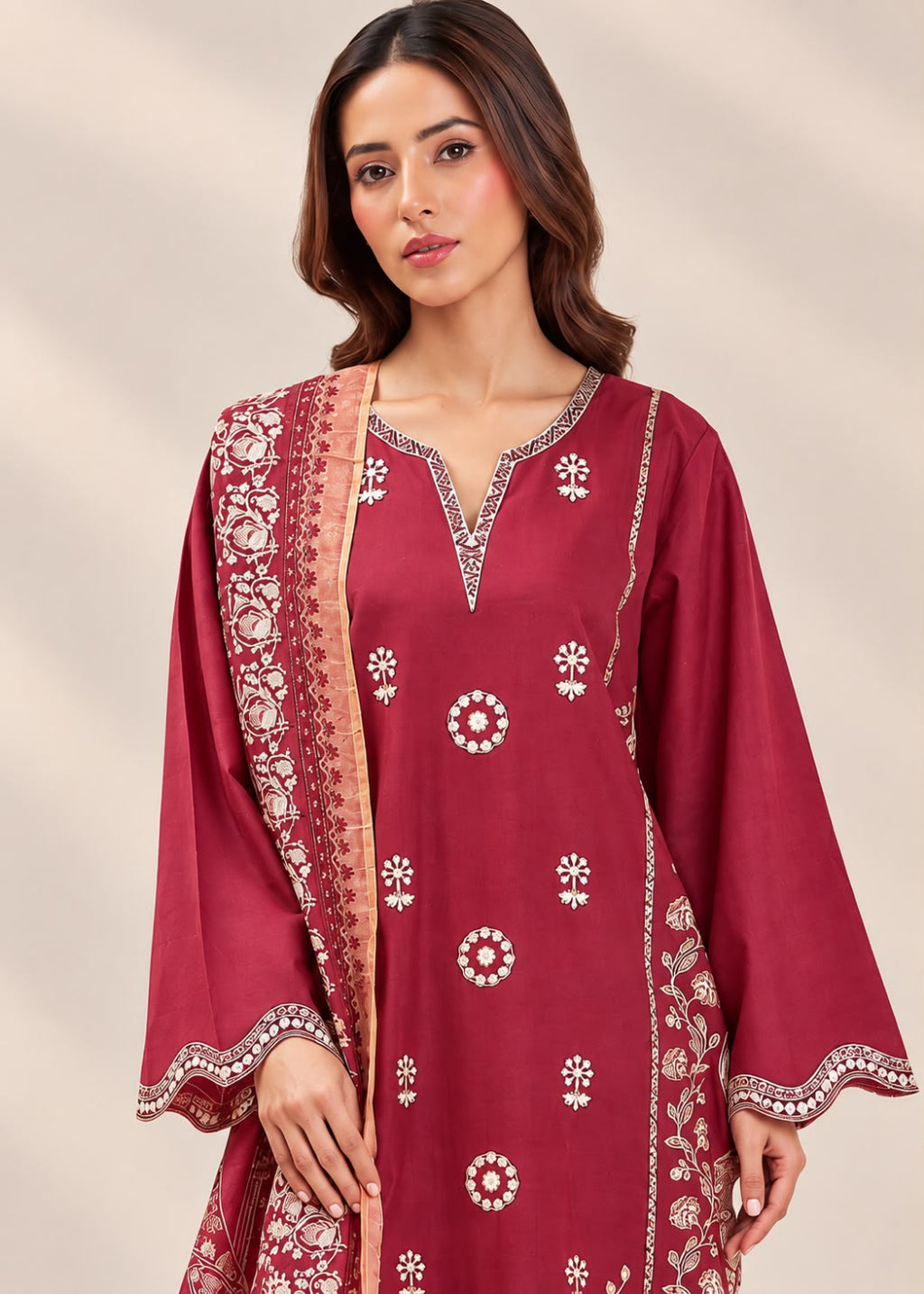 A woman modeling a deep maroon traditional kurta set with white floral embroidery and a matching dupatta, set against a neutral beige background.