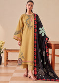 A woman models a traditional Indian salwar kameez suit set. The kurta is mustard yellow with colorful embroidery on the chest and sleeves, paired with matching trousers and a black dupatta featuring red scalloped borders and green and blue floral motifs.