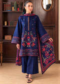 A woman models a navy blue embroidered traditional outfit consisting of a kurta, wide-leg trousers, and a matching dupatta, set against a warm wood-paneled background.