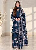 A woman modeling a navy blue three-piece traditional outfit with white palm tree and floral embroidery, featuring a kurta, matching trousers, and a dupatta, set against a warm beige interior background.