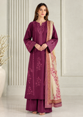 A woman models a traditional Indian salwar kameez suit in deep magenta with matching embroidered trousers and a beige dupatta featuring pink floral patterns and gold borders, set against a neutral paneled wall background.