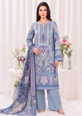 A woman modeling a light blue three-piece ethnic suit with intricate purple and blue printed patterns, featuring a long kurta, matching wide-leg trousers, and a coordinating dupatta, set against a white draped background with floral arrangements.
