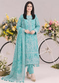 A woman modeling a traditional turquoise blue ethnic salwar kameez set with matching dupatta, standing in front of a white bicycle decorated with flowers against a light beige studio backdrop.