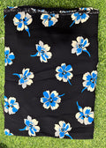 Black fabric with a blue and white floral print, laid flat on green grass.