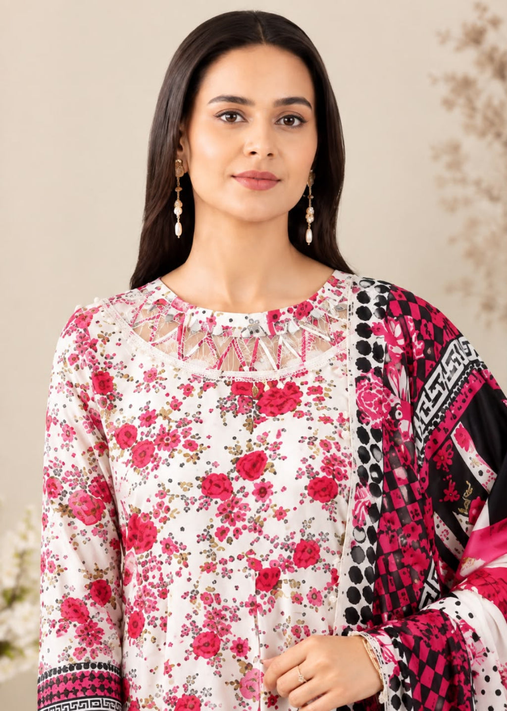 A woman modeling a traditional three-piece salwar kameez suit. The kurta is off-white with a vibrant pink and red floral print, featuring a decorative embroidered neckline.