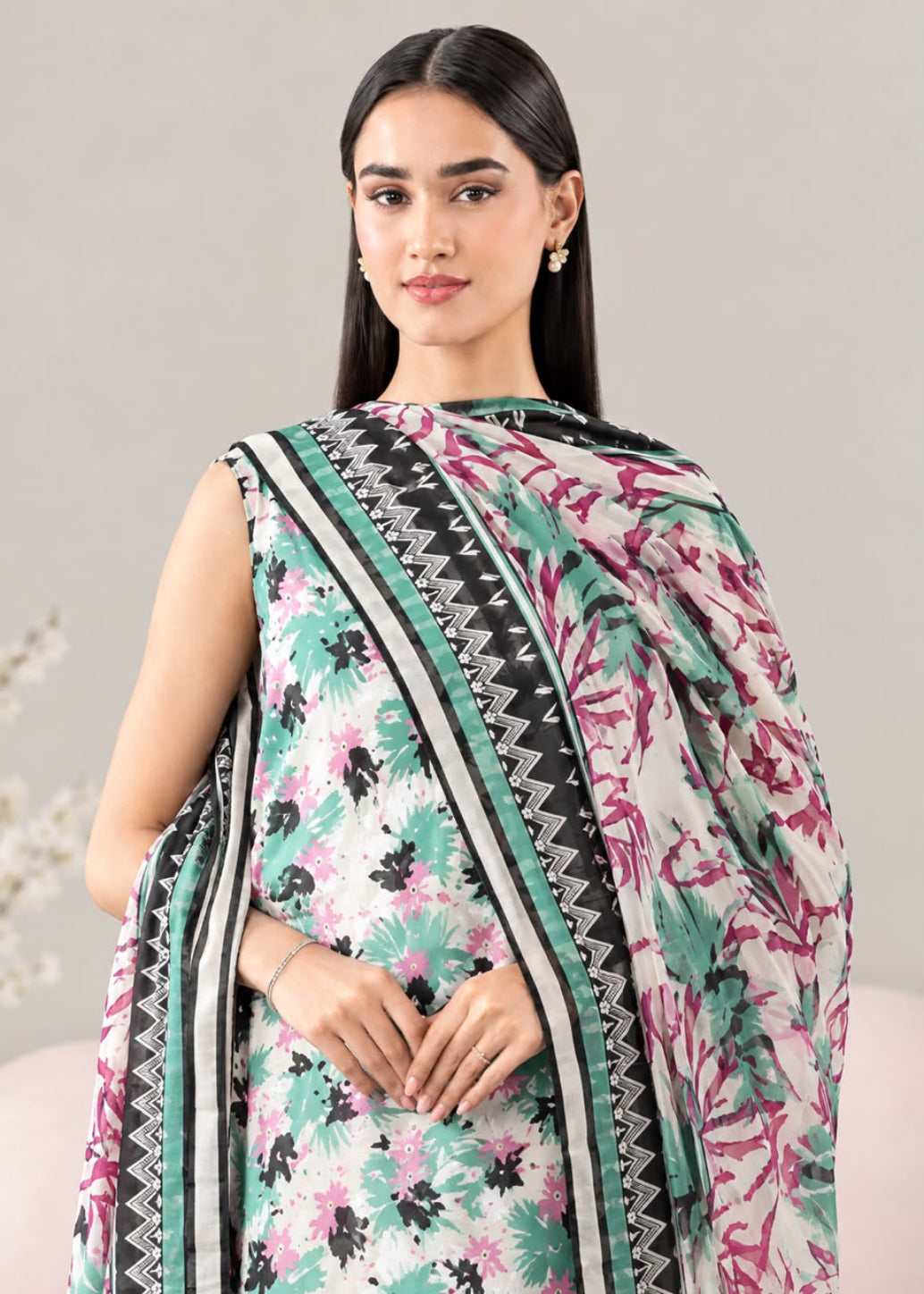 A woman modeling a sleeveless printed kurta with a matching dupatta. The fabric features a white base with green, pink, and black floral and botanical patterns, accented by black and green geometric borders.