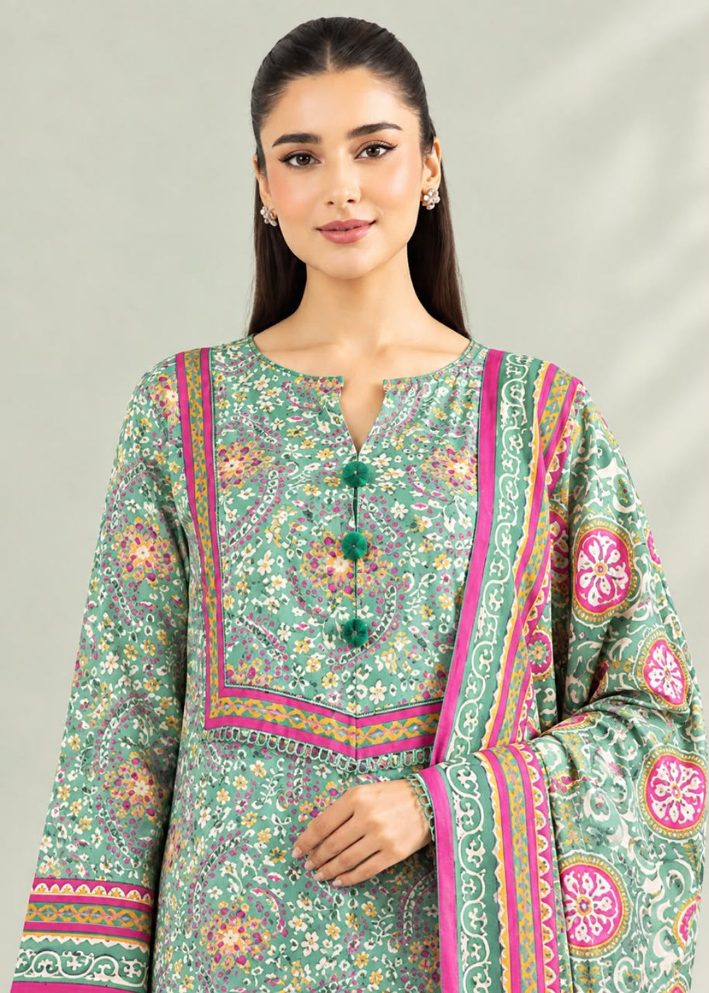 A woman modeling a green printed ethnic kurta with pink and orange border details and a matching dupatta, set against a plain light gray background.