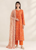 A woman modeling a traditional Indian outfit consisting of an orange kurta with white floral prints, matching orange pants, and a beige dupatta with orange floral patterns and tassel ends, set against a plain beige background.