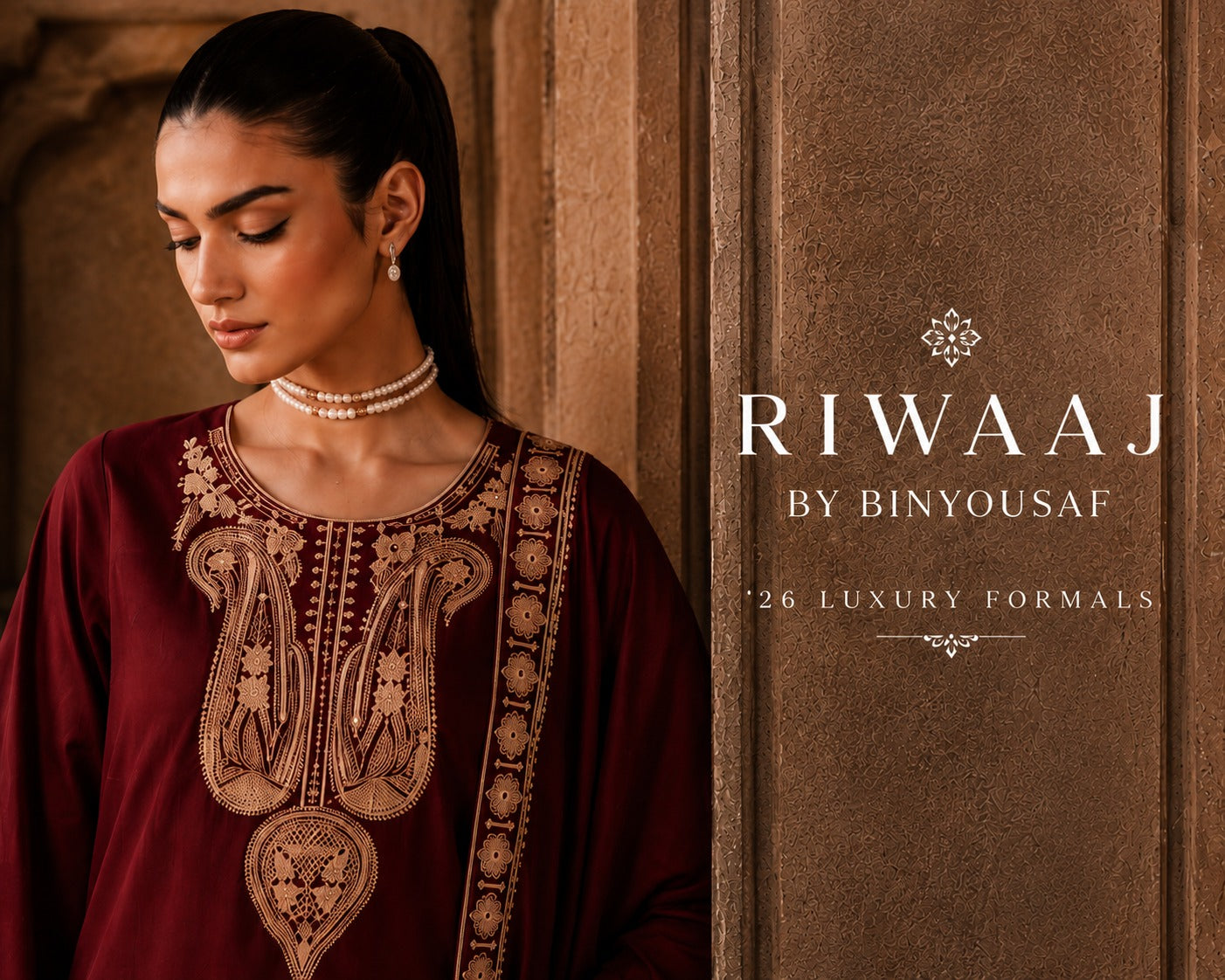 A woman wearing a deep maroon embroidered kurta with gold detailing, standing against a textured brown stone wall. The right side of the image features a text overlay that reads 'RIWAAJ BY BINYOUSAF *26 LUXURY FORMALS'.