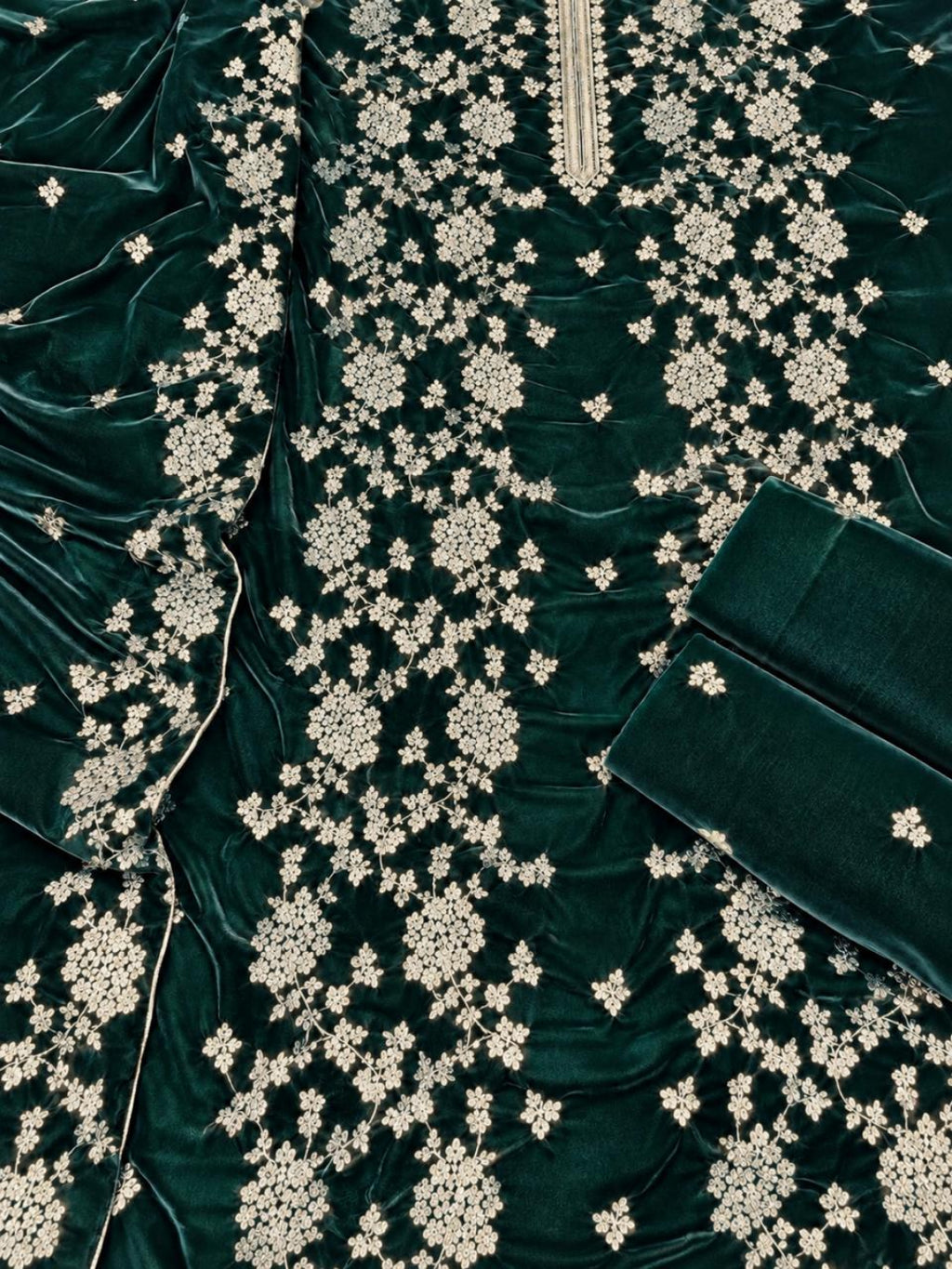 Dark green velvet fabric with intricate white floral embroidery and a matching folded fabric piece on a white background.
