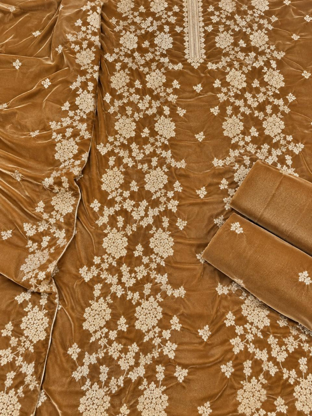 A close-up of a brown velvet fabric garment or textile with cream floral embroidery and matching rolled fabric pieces.