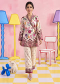 A woman models a traditional South Asian floral print kurta and pant set. The outfit features a warm beige base with a vibrant multicolor floral and paisley pattern in pink, red, green, and blue.